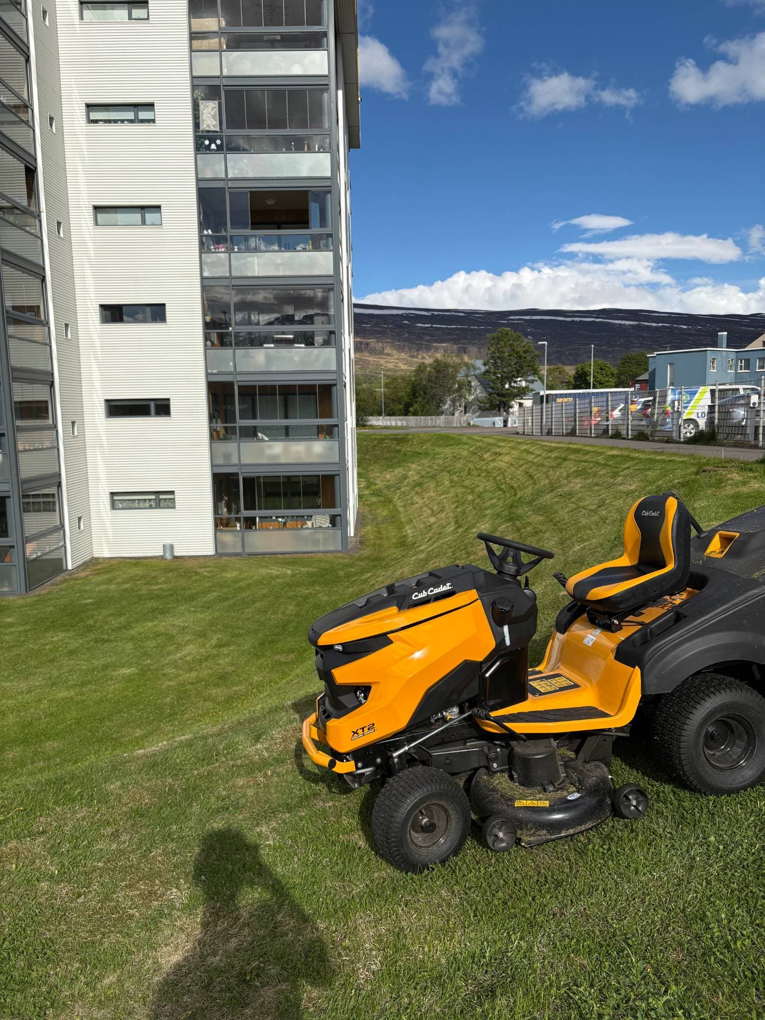 Sláttutraktor á grasflöt við fjölbýlishús